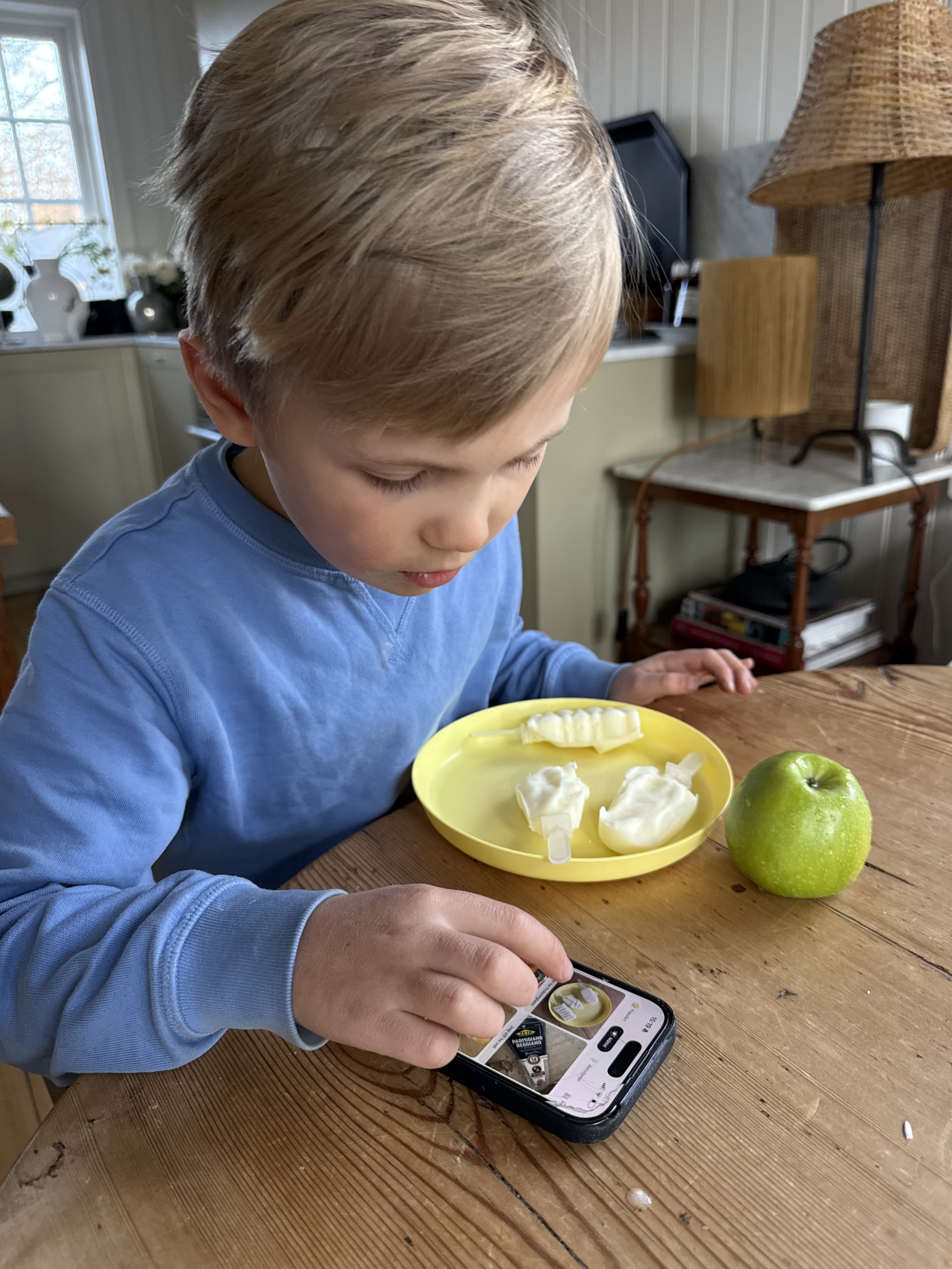 Tom using a phone at the kitchen table
